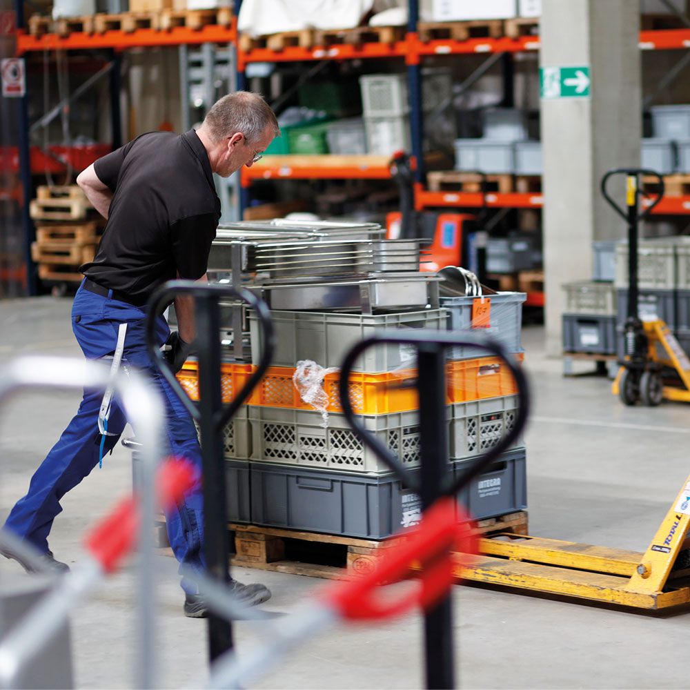 Zwei Arbeiter verladen Geschirr in einem Lager.